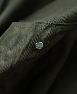 Olive herringbone fabric jacket button detail near the placket.