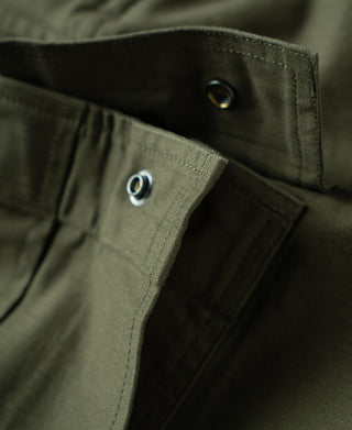 Olive cargo pants waistband close-up with metal snap closure and pocket seam