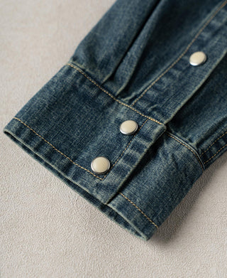 Washed denim shirt cuff with three snap buttons and contrast stitch lines