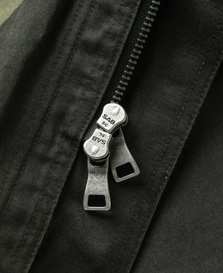 Field jacket zipper pull with gray metal slider and snap tab detail
