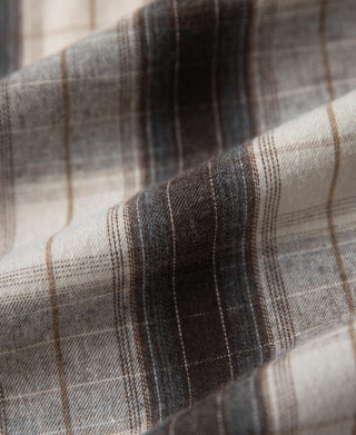 Plaid fabric close-up showing woven stripes in beige and dark tones