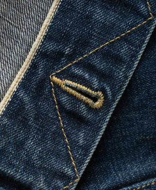 Indigo denim jacket pocket trim close-up with contrast yellow bar tack stitching