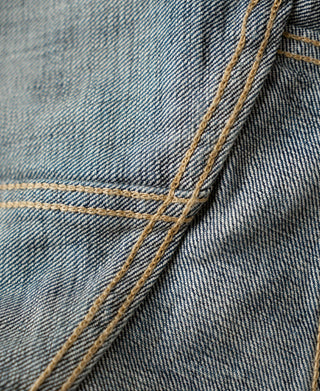 Indigo denim jacket seam close-up with double rows of contrast yellow stitching