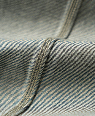 Sage blue denim fabric close-up showing seam and curved panel stitching