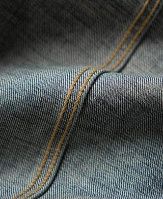 Indigo denim jacket fabric and seam close-up with layered contrast yellow topstitching