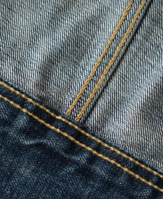 Close-up of indigo denim panel with yellow topstitching seam detail