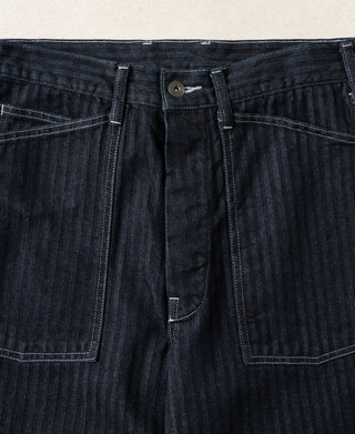 Indigo denim fatigue pants close-up of waistband, button closure, and front pockets