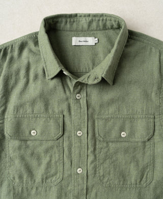 Sage green work shirt close-up: button placket, pointed collar, and two chest pockets.