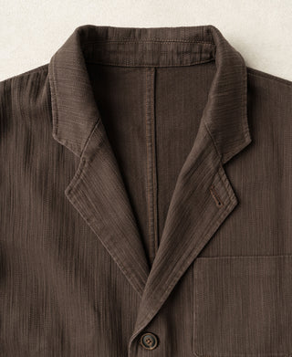 Brown herringbone blazer lapel with two-button front and welt pocket detail
