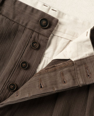 Brown herringbone waistband detail with dark button placket and pleats