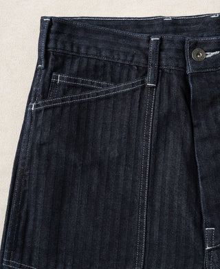 Indigo herringbone denim pants front view with pleated seat and utility pocket details