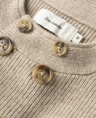 Ecru knit cardigan neckline close-up with logo label and large button details.