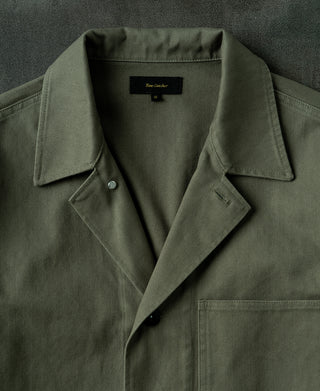 Olive field jacket with notch collar and dark button front placket.