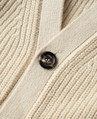 Close-up of a dark button on the natural cotton cardigan's textured rib knit