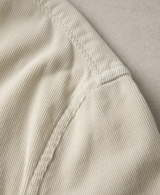 White corduroy fabric close-up with shoulder seam detail