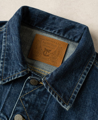 Indigo denim jacket with brand patch inside collar and snap-button placket