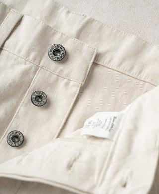 White pants front with three button closures and small fabric label at waistband