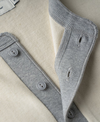 Henley shirt button placket detail with gray trim and two round buttons