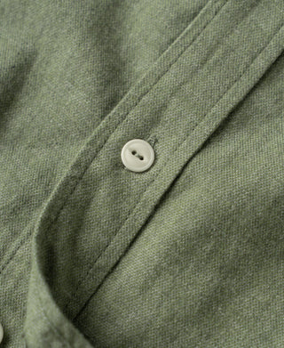 Sage green work shirt button-front and pointed collar detail with round white button.