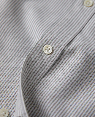 Oxford shirt sleeve cuff close-up, blue-and-white stripe with round button.