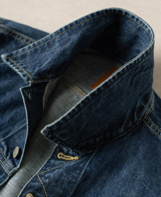 Indigo denim jacket showing inner placket, folded collar, and button closure
