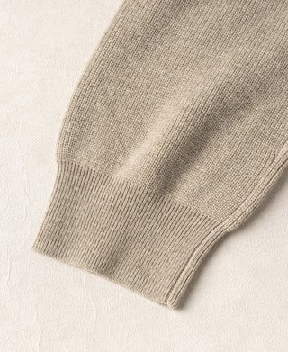 Ecru knit cardigan sleeve cuff with ribbed cuff edge and textured weave.
