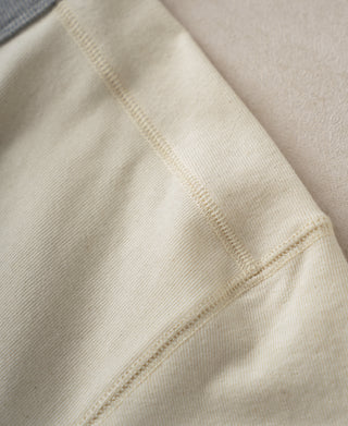 Close-up of cream cotton henley shirt fabric with stitched seam detail