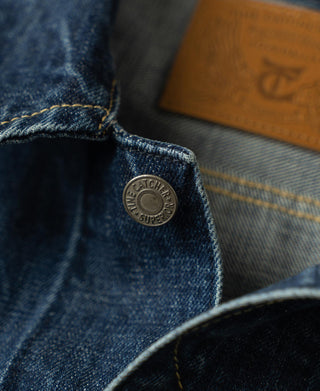 Close-up of indigo denim jacket yoke with round metal snap button