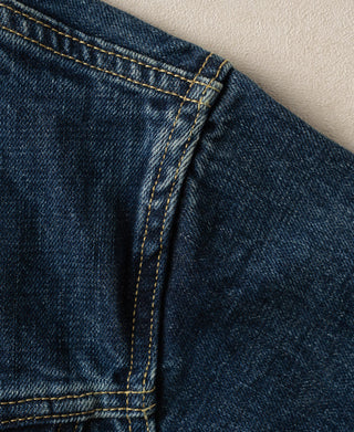 Indigo denim jacket side seam and pocket flap with double-row yellow stitching