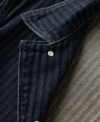 Indigo denim jacket yoke seam with button at collar edge