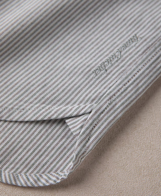Oxford shirt hem close-up, blue-and-white stripes with side vent stitching.