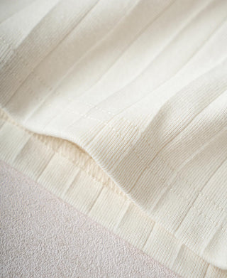 Oatmeal ribbed cotton T-shirt hem close-up with stitched edge