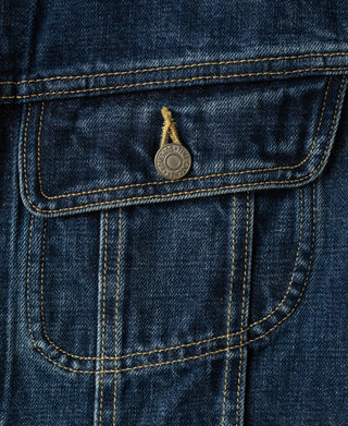 Front flap pocket detail on indigo denim jacket with round metal button