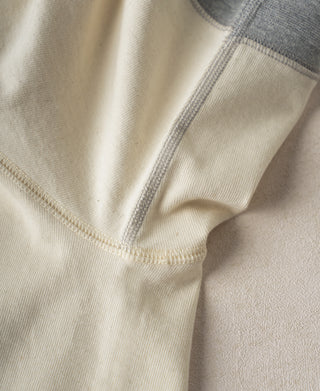 Close-up of cream cotton henley hem and ribbed collar edge with gray inner trim