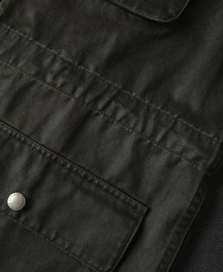 Field jacket seam and pocket flap stitching detail with round metal snap