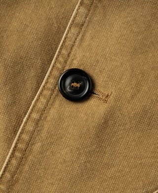Close-up of a black button on the jacket's khaki canvas front