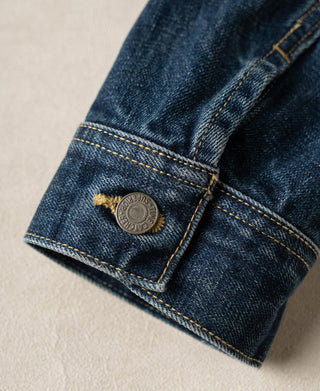 Indigo denim jacket sleeve cuff with metal button and yellow topstitching