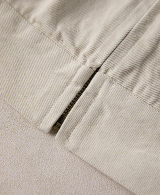 Natural twill Eisenhower jacket front placket with zipper edge and pocket seam.