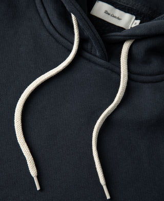 Close up of the cream drawstrings and neckline construction on the dark blue heavyweight cotton hoodie