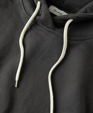 Close up of the cream drawstrings and neckline construction on the dark gray heavyweight cotton hoodie
