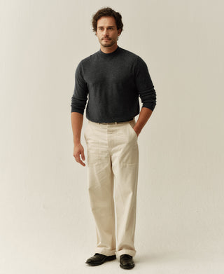 Man wearing a heather gray merino wool mock neck sweater styled with cream trousers for a refined minimalist look