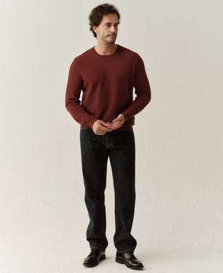 Man wearing a jasper red merino wool crewneck sweater with a classic minimalist fit