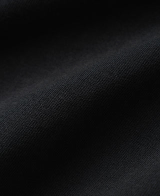 Close-up view of the dense loopwheel cotton fabric texture and soft surface of a navy Henley shirt.