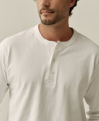 White henley neckline close-up with short button placket and collar trim.