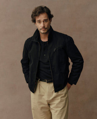 Black cossack jacket with standing collar, hand pockets, and snap front