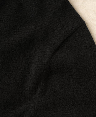 Black merino wool sweater sleeve seam detail.