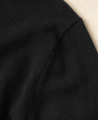 Black knit sweater sleeve with subtle texture and clean seam detail