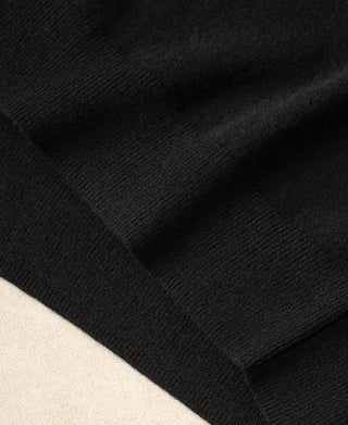 Black merino wool sweater ribbed cuff texture close-up.
