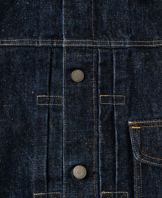 Close-up of dark indigo denim fabric with contrast yellow stitching, metal buttons, and a pocket detail.