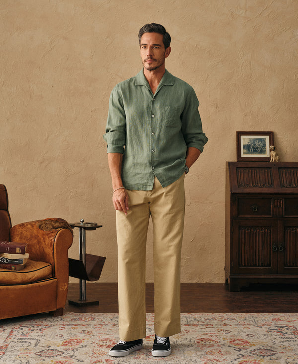 Sage green linen shirt on model with button placket, paired with light pants
